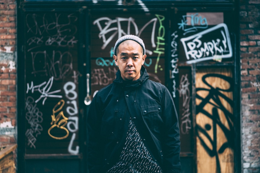 Jeff Staple standing in front of graffiti wall.