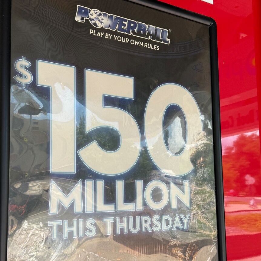 A dark blue sign advertising a $150 million lottery prize is mounted on a shiny red wall.
