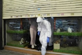 Officers in protective suits leave a closed pet shop.