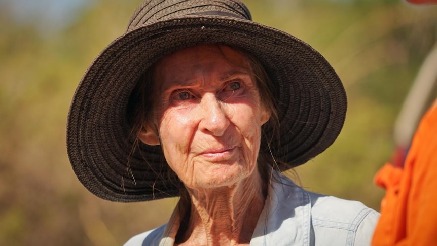 Rural Darwin resident Nancy Nathanael speaks to a man in an orange fire fighting suit outside in her property.