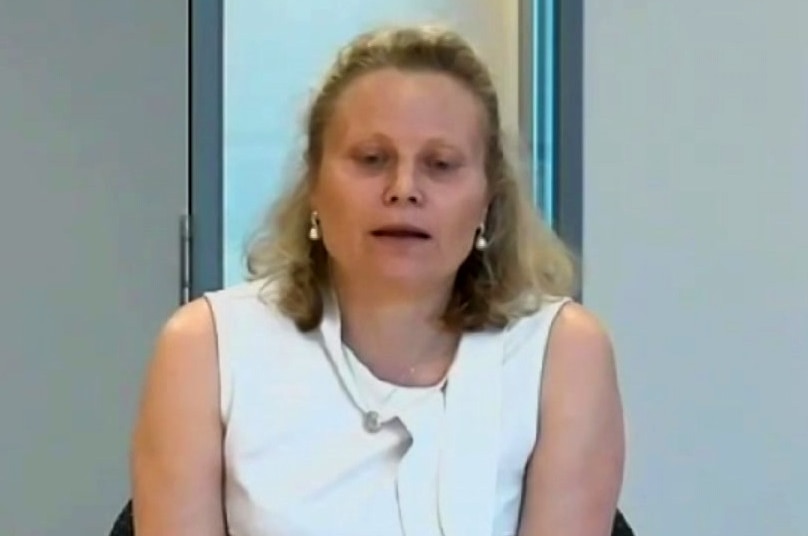 Kym Peake a woman with blond hair, wearing a white top, testifying at a public inquiry.