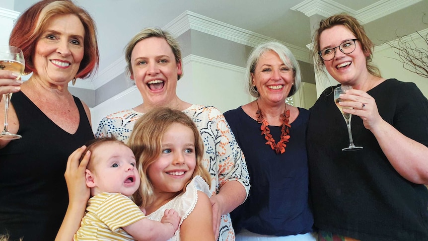 Melbourne mums Mel Currey and Hylton Shaw enjoy champagne with their families after arriving in Queensland.