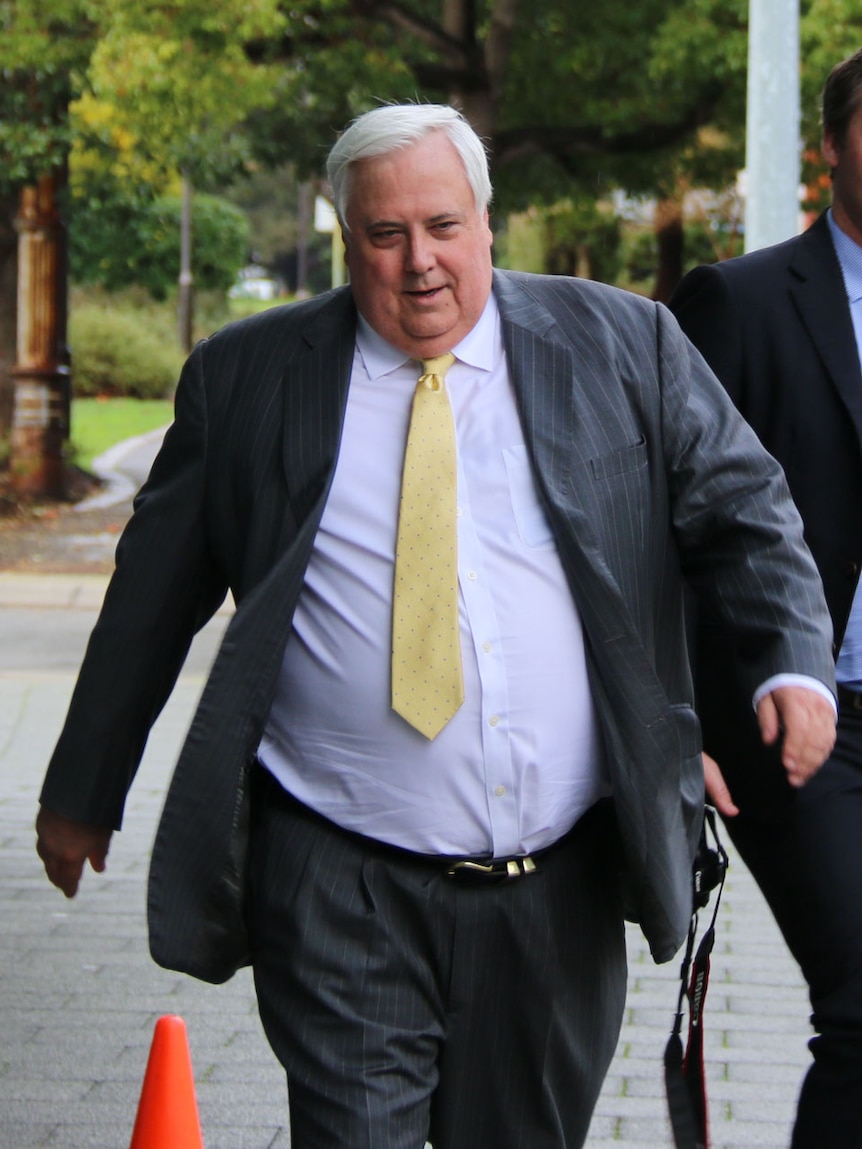 Clive Palmer, wearing a suit, walks down the street.