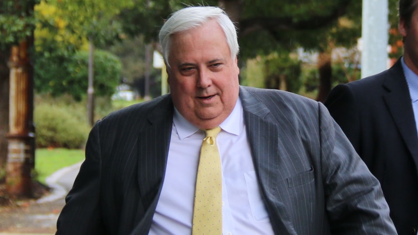 Clive Palmer, wearing a suit, walks down the street.