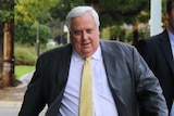 Clive Palmer, wearing a suit, walks down the street.