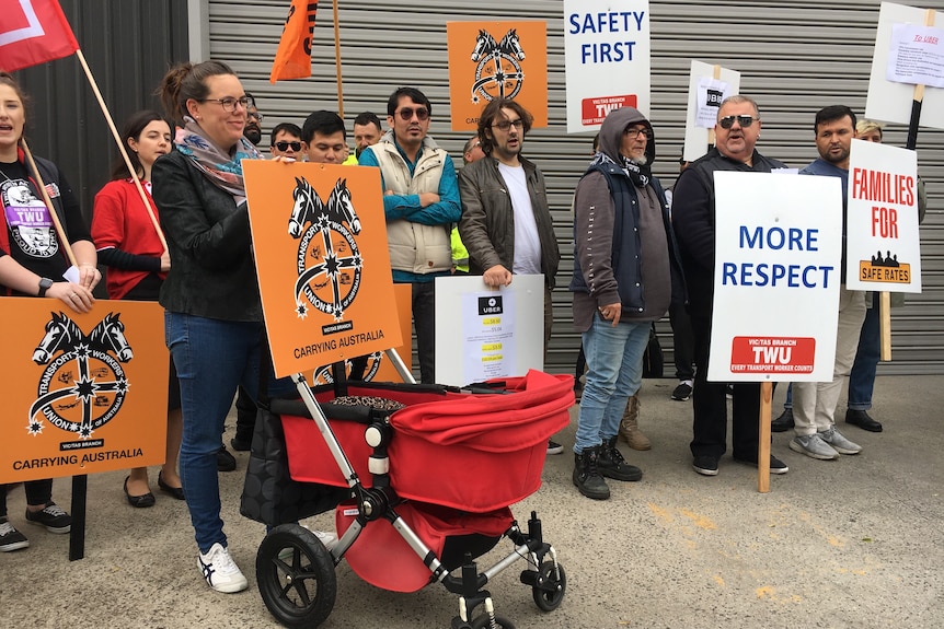 Protestors holding union placards gather outside Uber's Melbourne office.