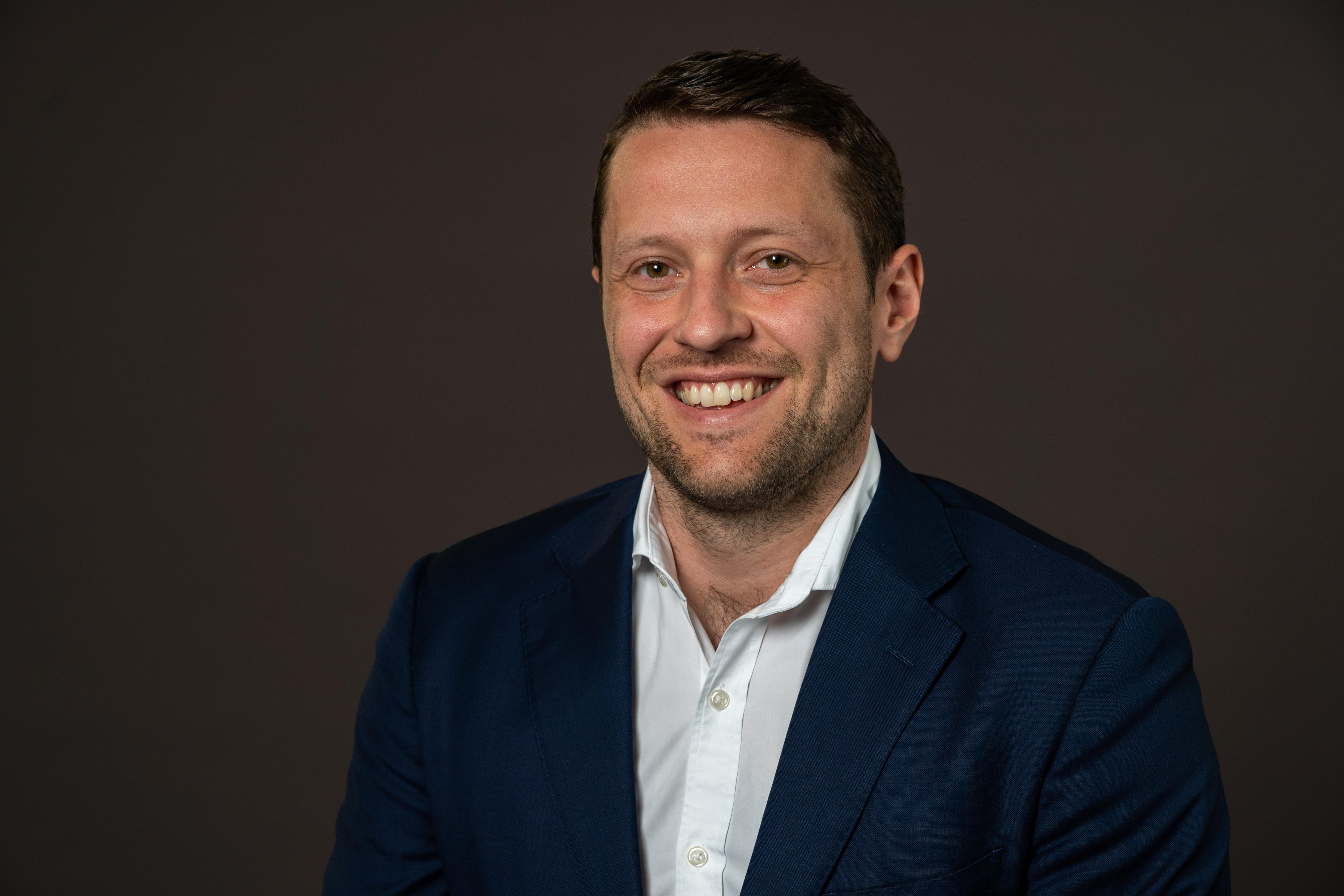 Um homem de terno sorrindo.