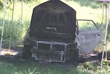 A burnt-out shell of a car viewed from the front.