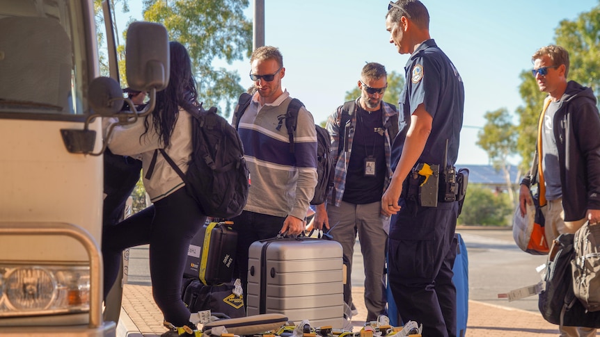 SA Police officers outside a bus with luggage arriving in Alice Springs.