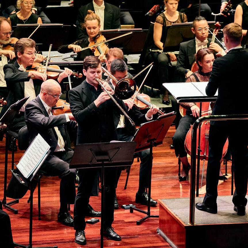 Australian trombone soloist Jonathon Ramsey playing on stage with the Melbourne Symphony Orchestra.