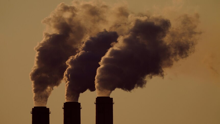 A file image of smoke stacks against a yellowish sky. 
