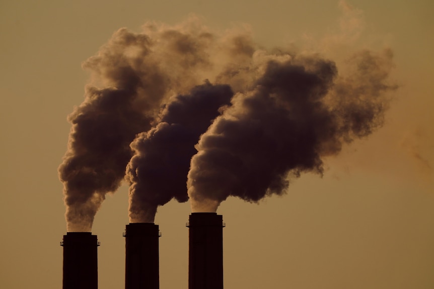 A file image of smoke stacks against a yellowish sky. 