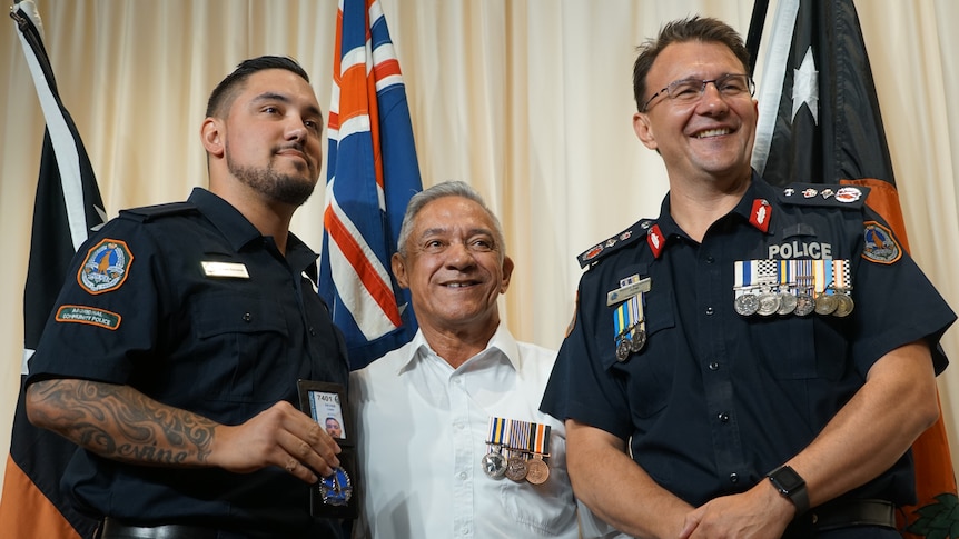 A new Aboriginal police officer smiling with his badge and his uncle and police commissioner Reece Kershaw