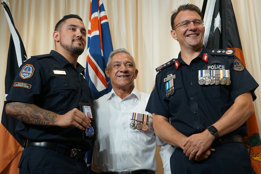 A new Aboriginal police officer smiling with his badge and his uncle and police commissioner Reece Kershaw
