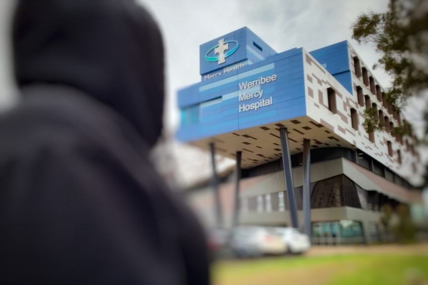 A dark blurred figure in front of the Werribee Mercy Hospital.