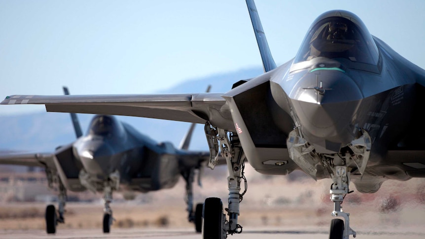 Dark military aircrafts viewed head-on on a runway