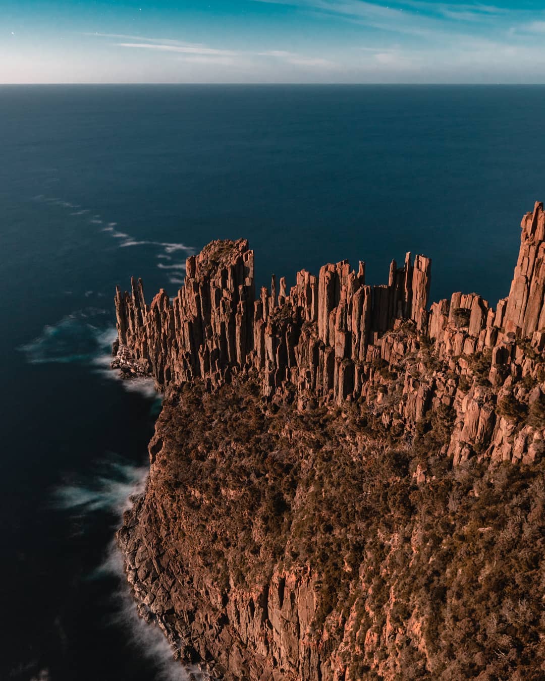 Tall columns of rock form jagged cliffs on a coastline.