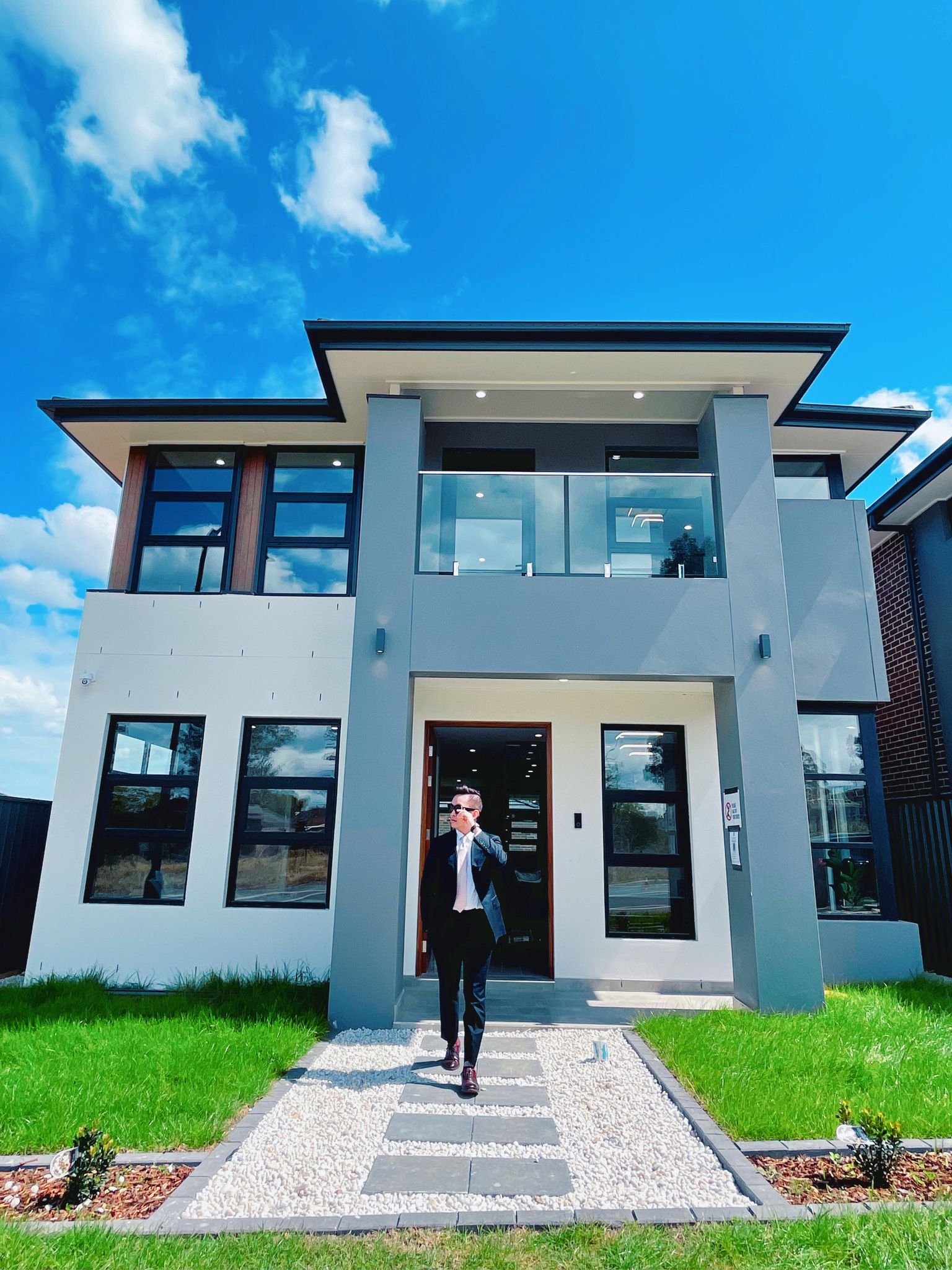 A man in a suit walks in front of a modern-styled home