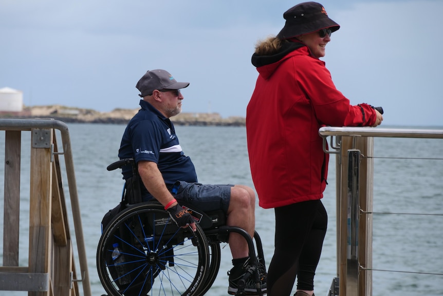 A man in a wheelchair and a woman stand on a pier in Bunbury.