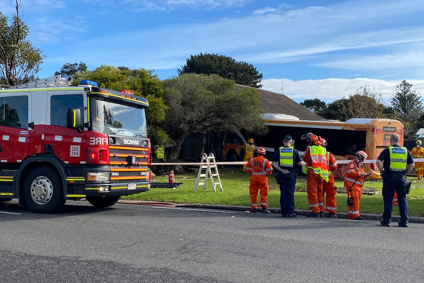 Police and SES attend the scene where a bus has crashed into a house.