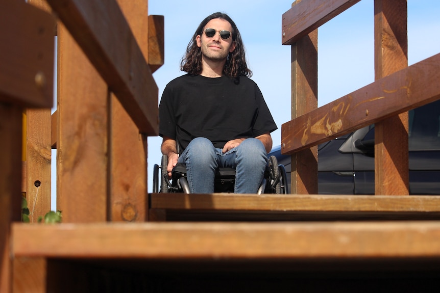 He sits at the top of beach stairs in his wheelchair