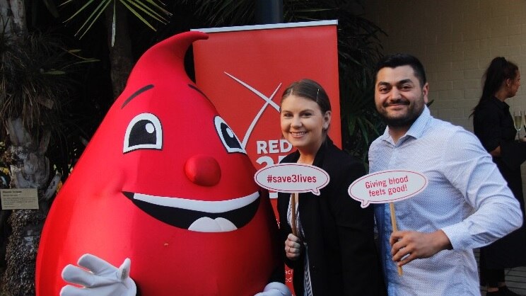 Michelle Climpson and husband Jamie Deubago hold up signs about blood donation