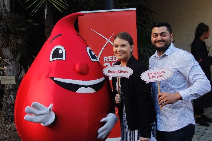 Michelle Climpson and husband Jamie Deubago hold up signs about blood donation