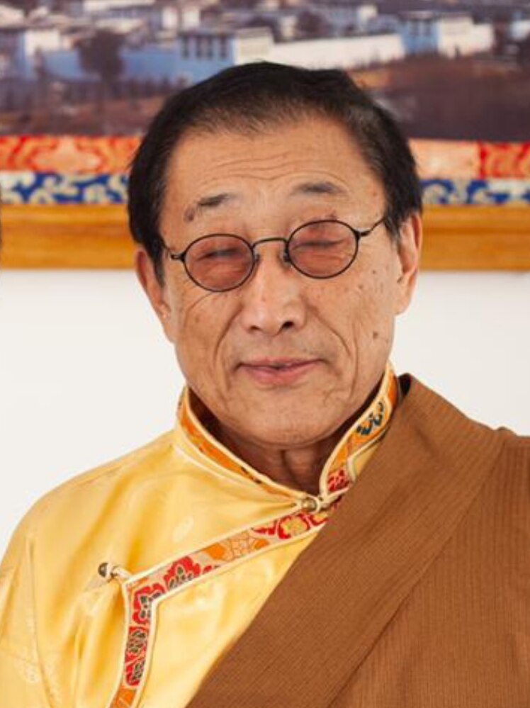 A profile photograph of an elderly Tibetan man in traditional dress.