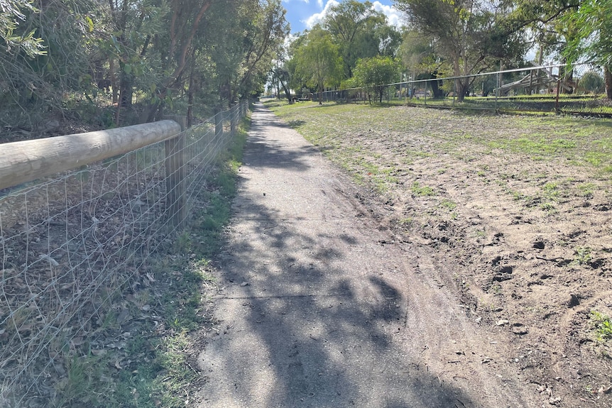 A footpath with fencing along the left and grass on the right