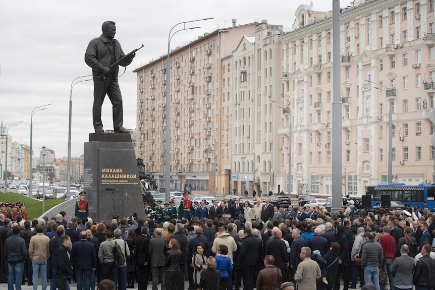 A wide shot of the Russian firearm designer Mikhail Kalashnikov monument with a crowd of people gathered around it.