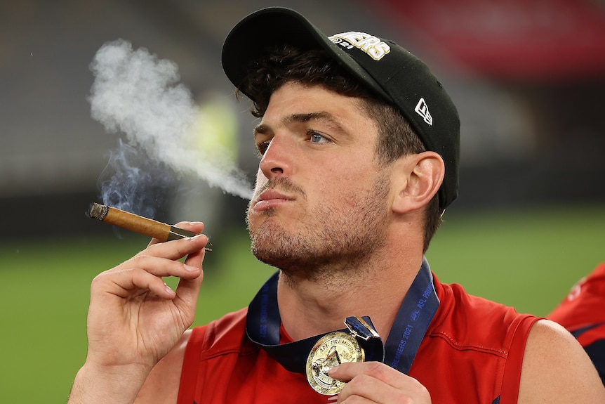 Angus Brayshaw smokes a cigar while on the field after the 2021 grand final.
