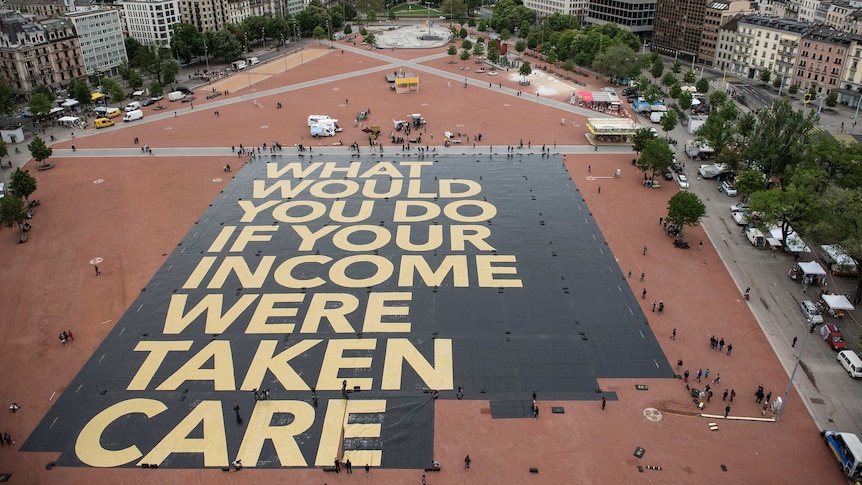 Universal basic income activists install a poster in a public square in Geneva, Switzerland.