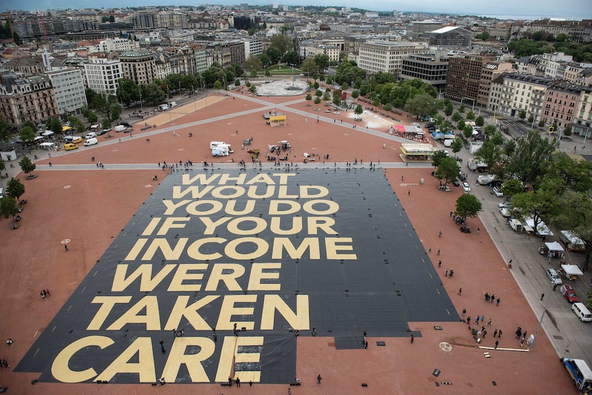 Universal basic income activists install a poster in a public square in Geneva, Switzerland.