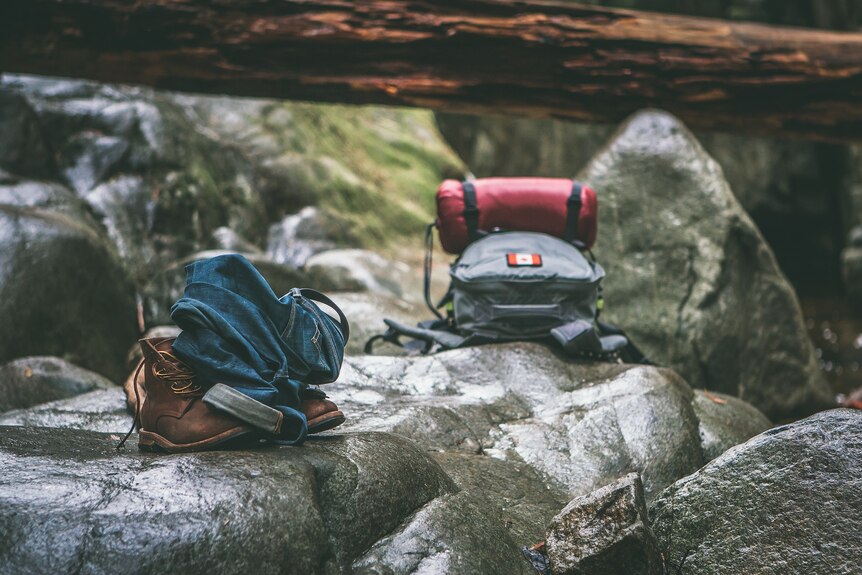 Backpacks and hiking gear lie abandoned on some rocks.