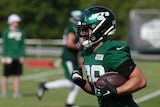 Valentine Holmes runs with the ball in full NFL gear at a New York Jets training session.