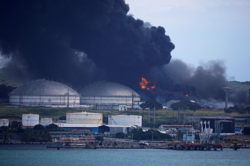 Fire burns close to two large fuel storage tanks