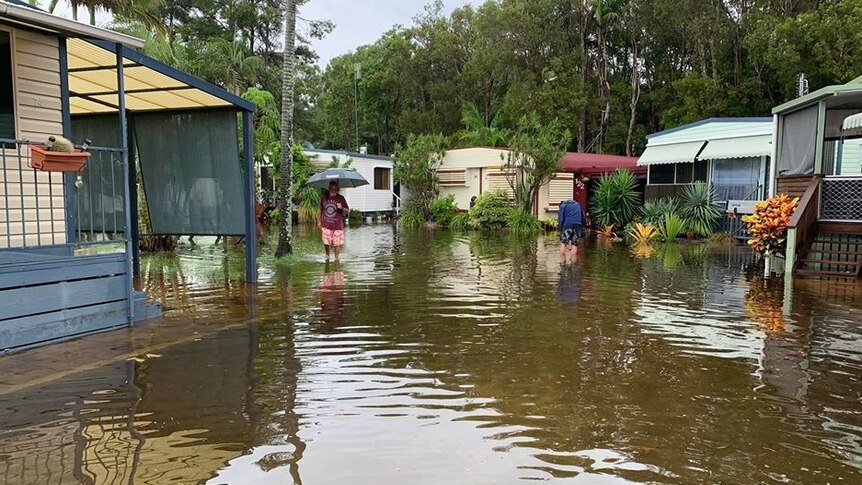 Floodwaters reach the doors of caravans as residents wade through the water