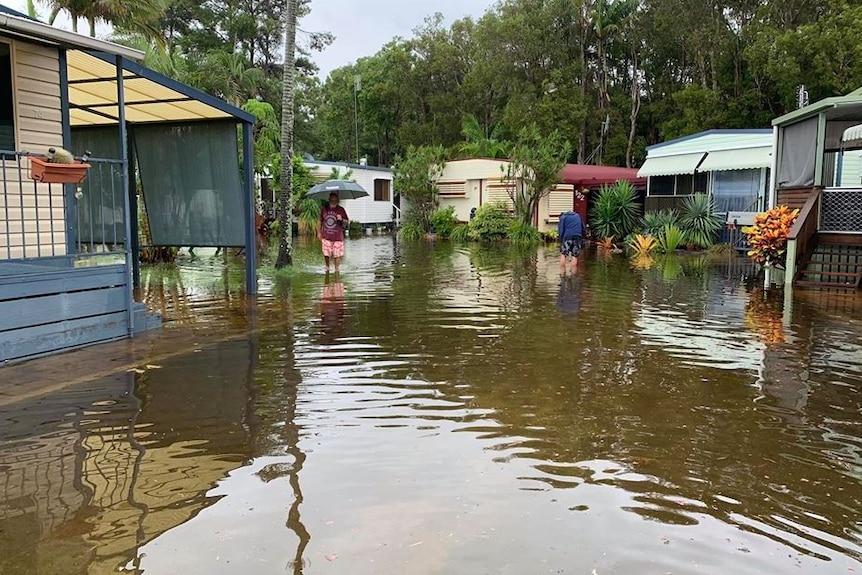 Floodwaters reach the doors of caravans as residents wade through the water