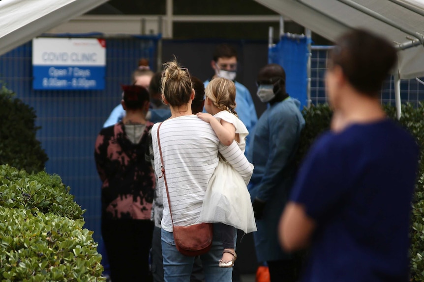 A mother and her young daughter queue outside a COVID Clinic based at Royal Perth Hospital