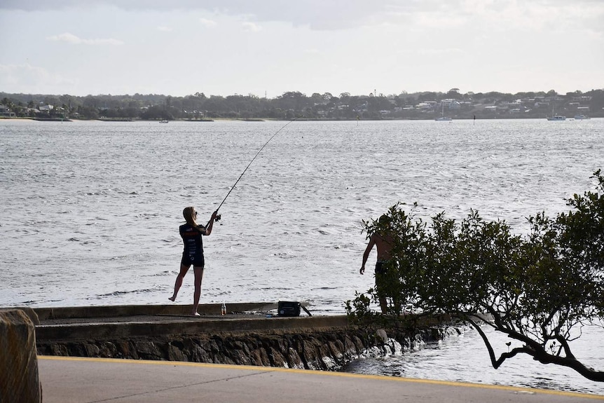 Man fishes off a jetty.