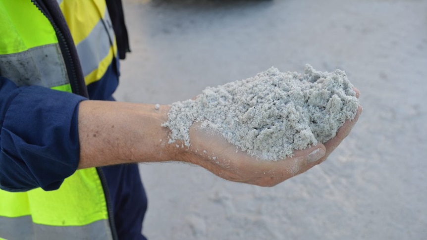 A man holds a handful of lithium.