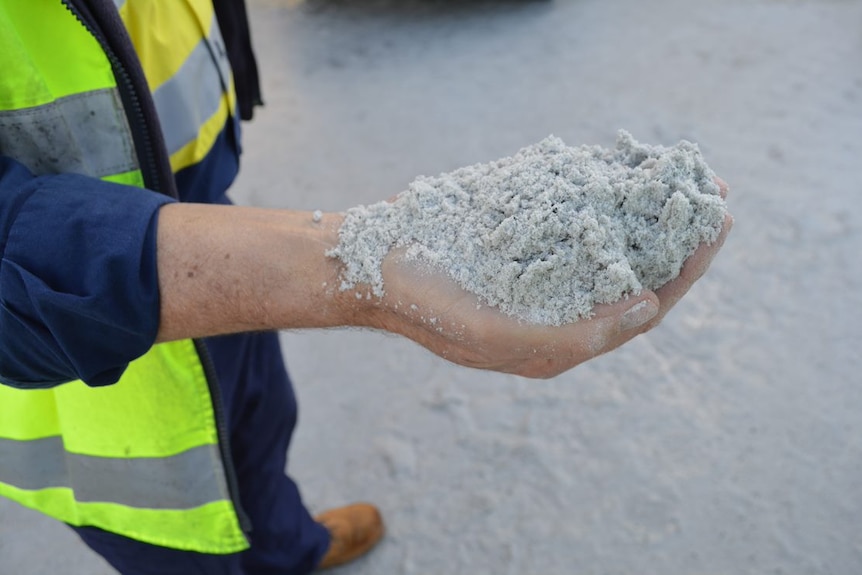 A man holds a handful of lithium.