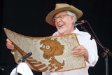 Rolf Harris laughs as he plays his 'wobble board'