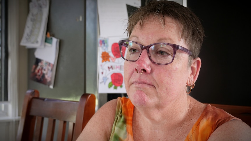 A woman with short hair and glasses, she has a side expression on her face