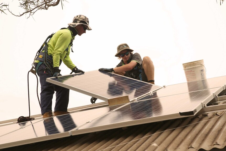 Electricians Lochie Barclay (r) and Jayde Ralph installing solar panels on a house in Broome.
