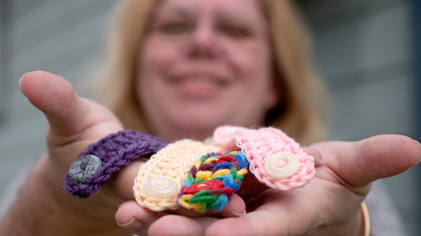 Woman face in background holds up handfuls of ear savers close to camera