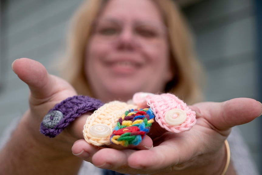 Woman face in background holds up handfuls of ear savers close to camera