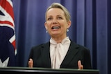 Susan Ley talks while standing behind a lectern. Behind her is an Australian flag.