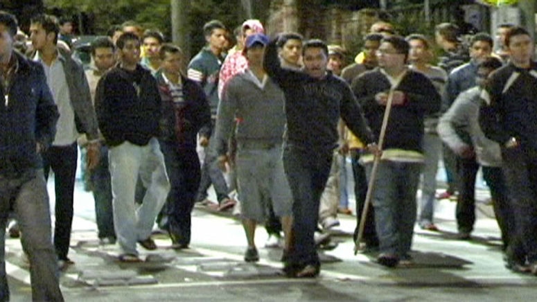 A man holding a stick leads a group of Indian students in protest in Western Sydney.