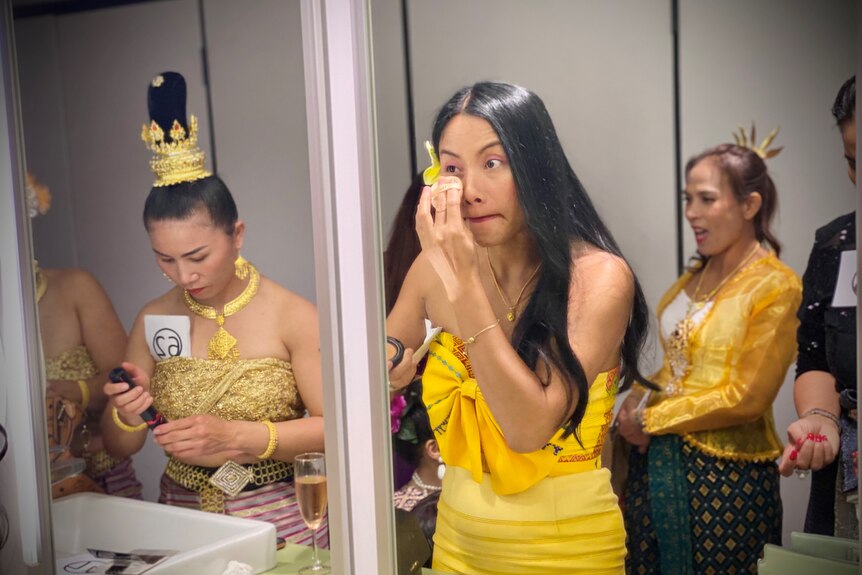 A woman applying makeup in a mirror